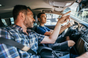 Teenager driving with his father